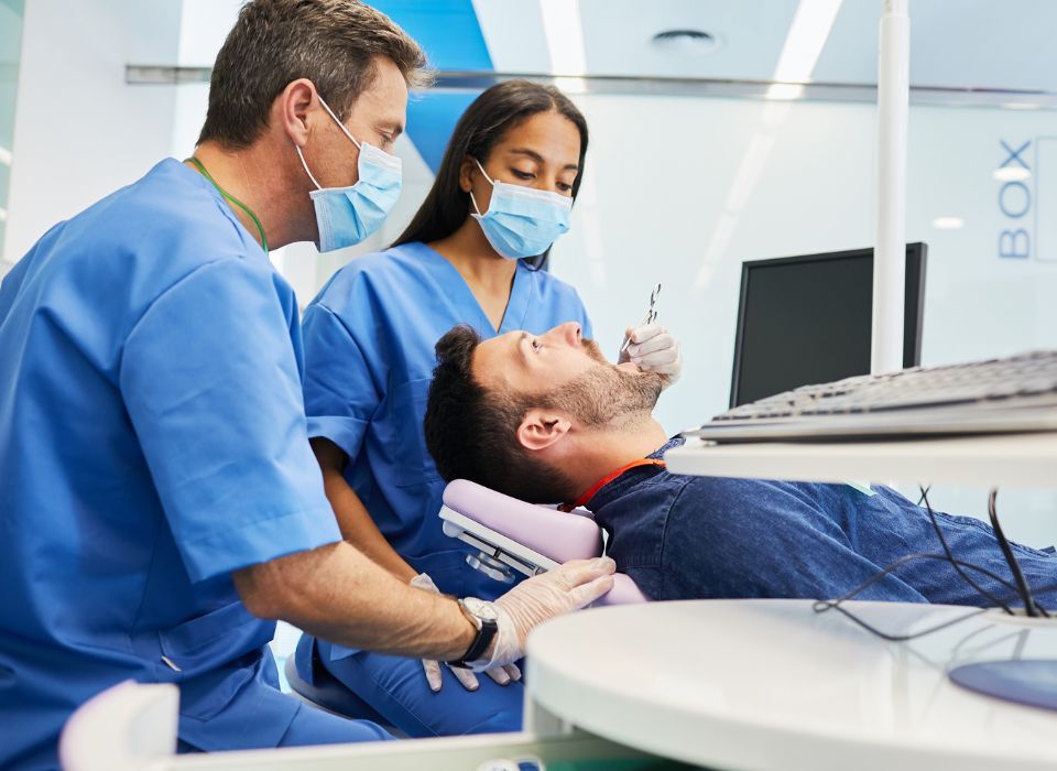 Dentist and assistant examining a patient's teeth in a dental office.