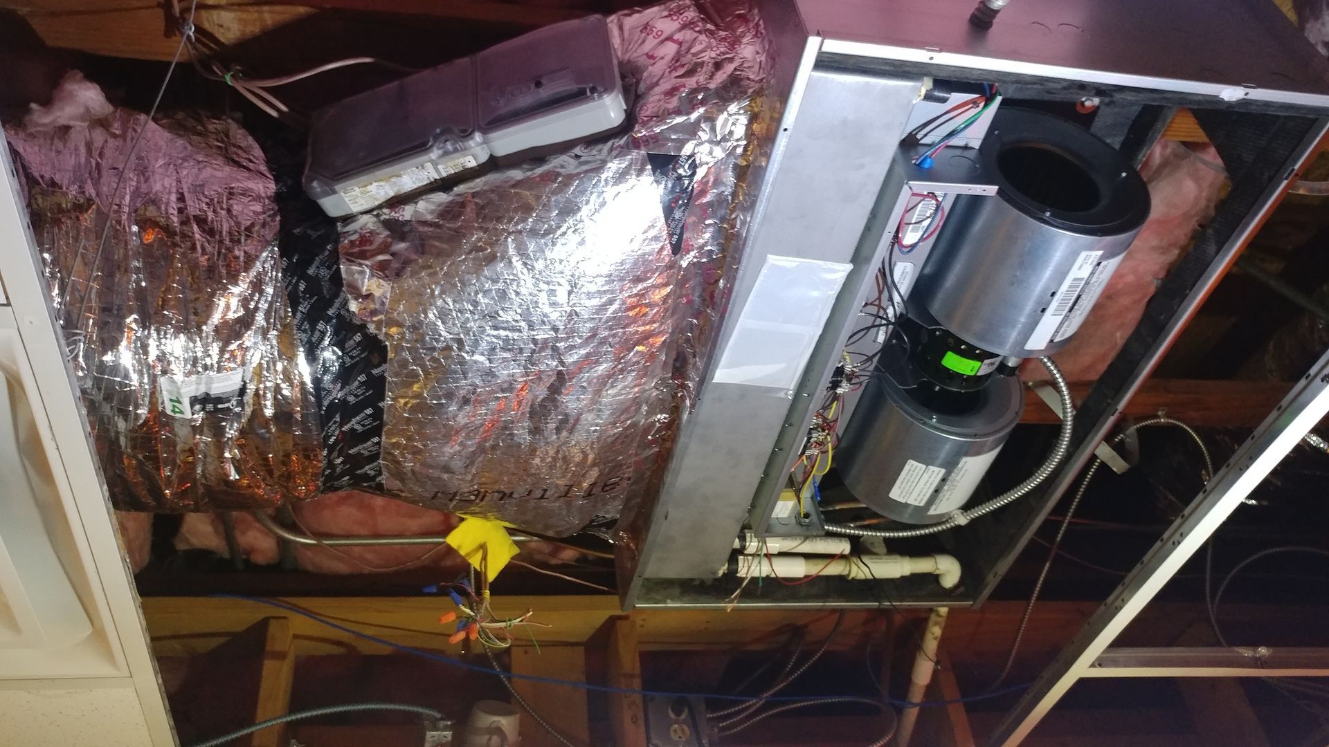 Exposed ceiling with insulation, ductwork, and two cylindrical HVAC units mounted overhead.
