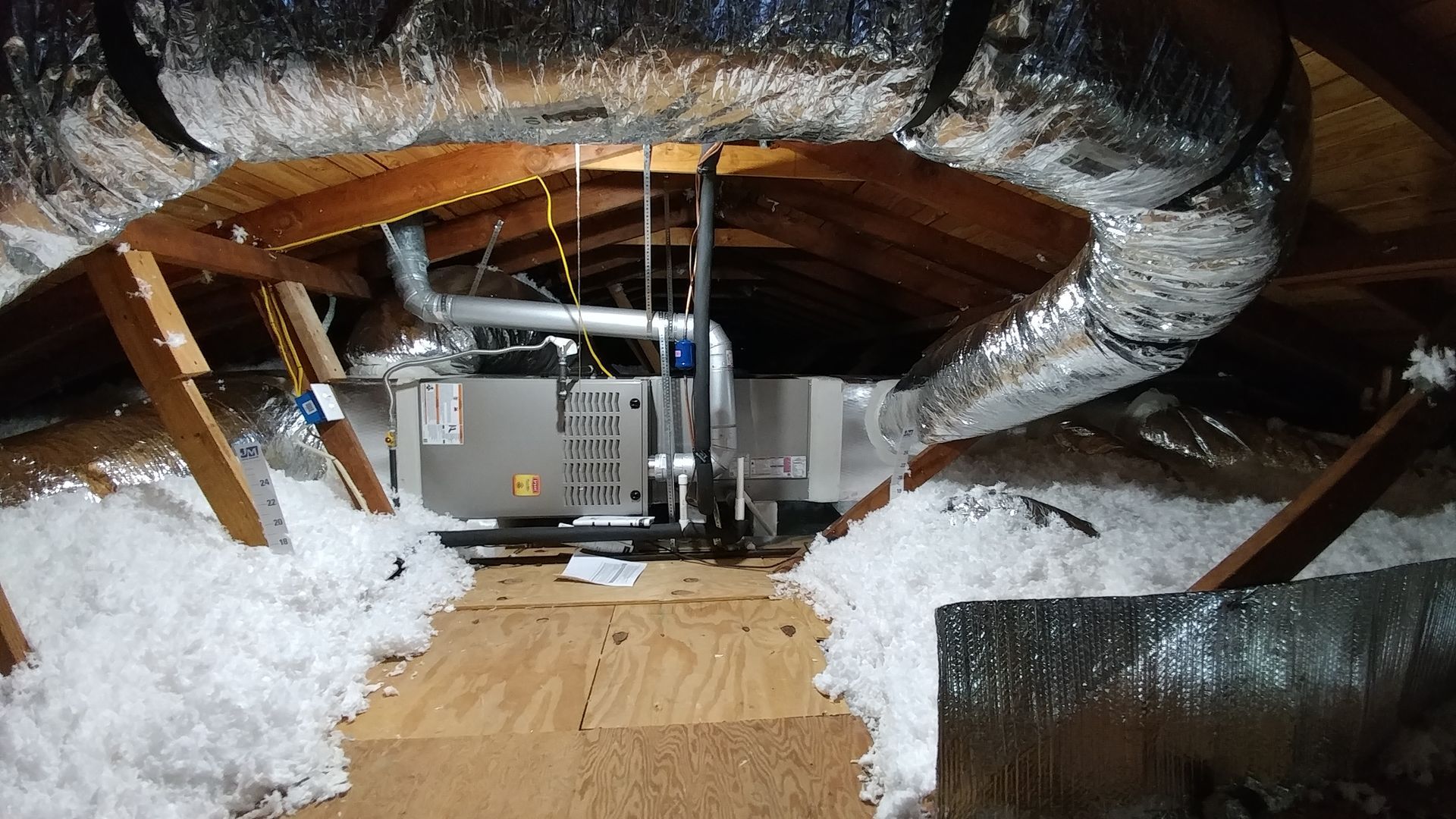 Attic with HVAC unit, insulation, and exposed ductwork under a sloped roof