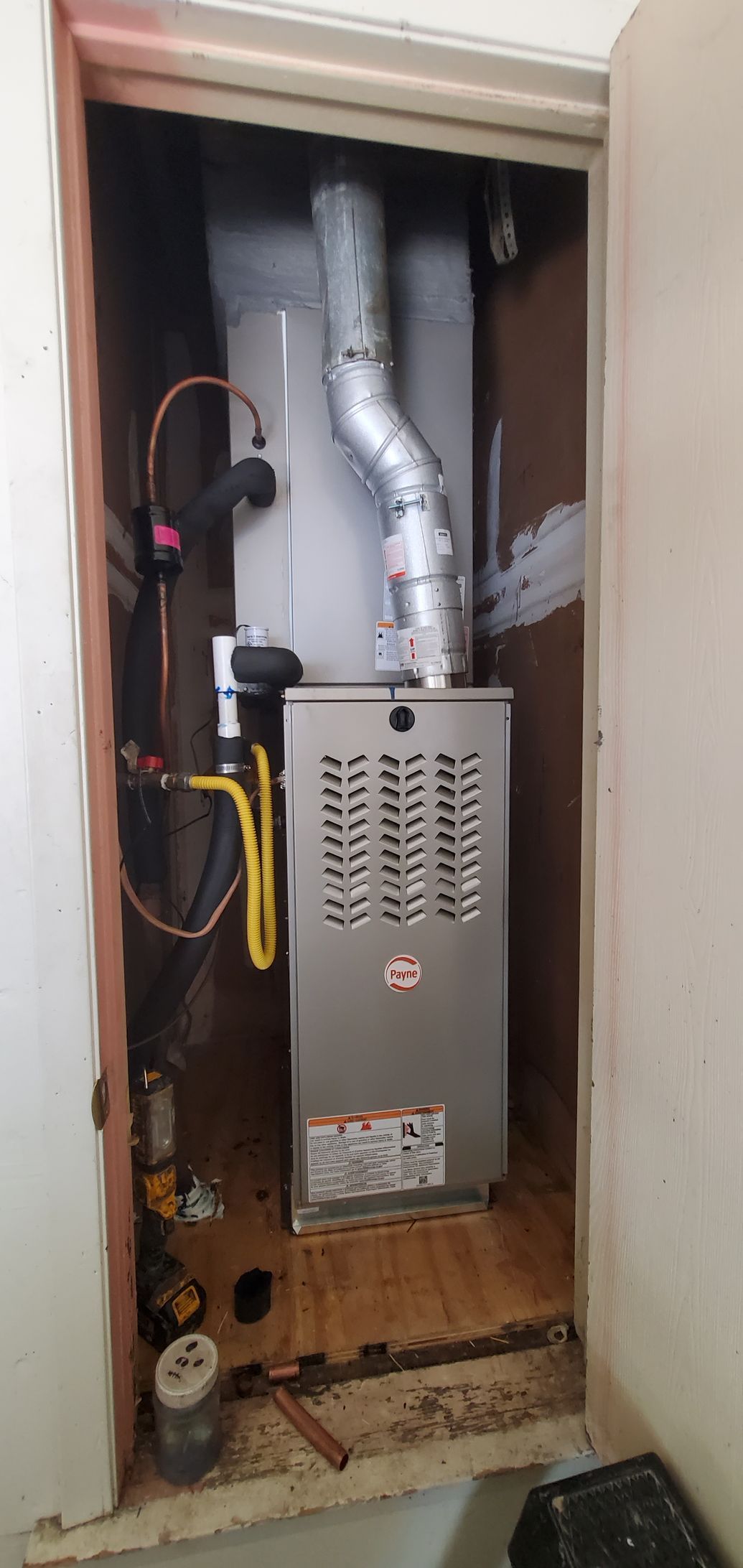 Open furnace cabinet with exposed ductwork, wiring, and metal unit inside a closet.