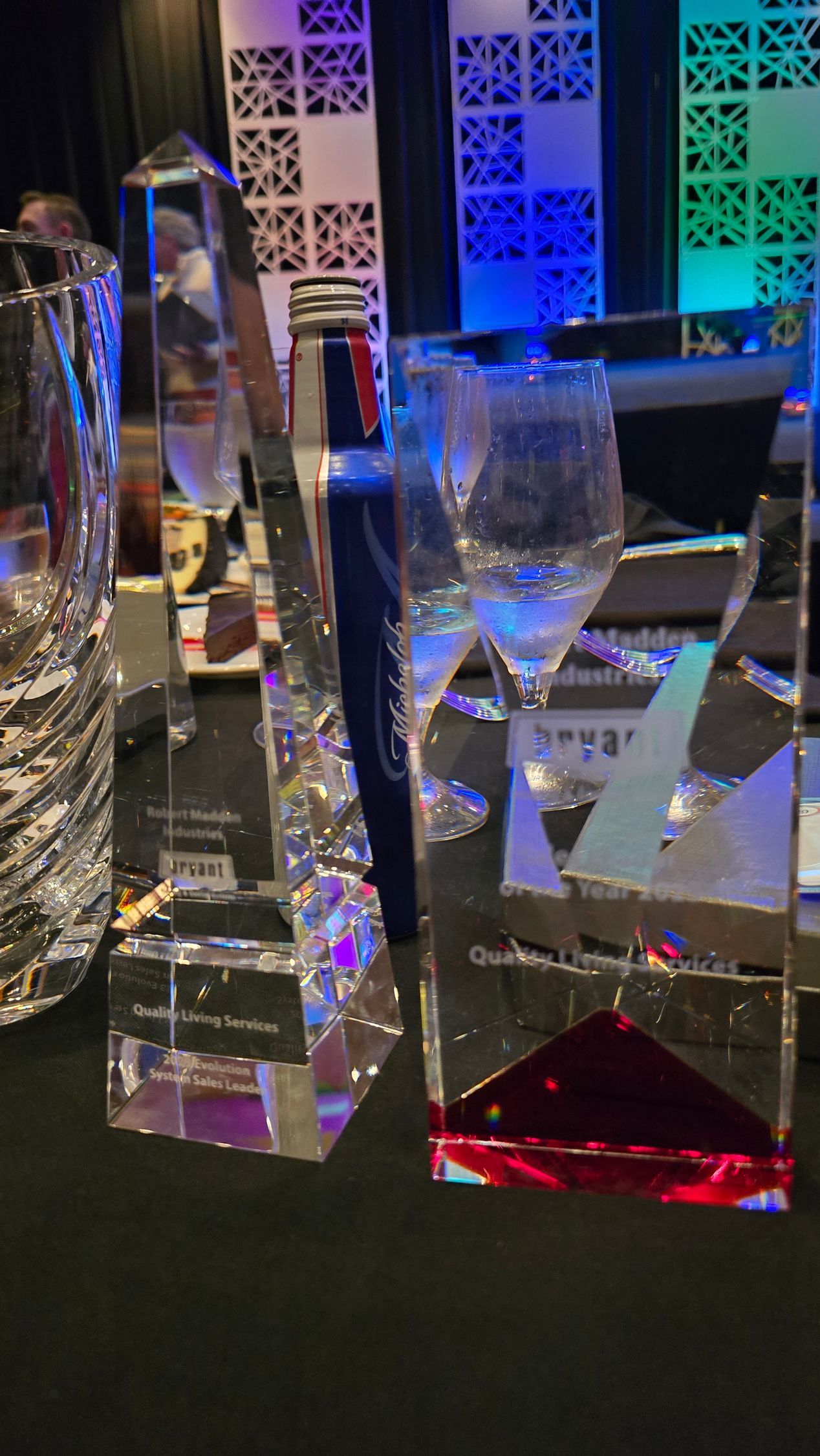 Glass awards on a table under blue and purple lighting at an event