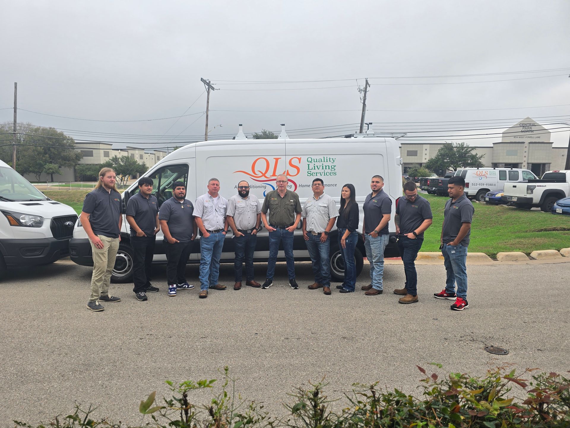 Group of people standing in front of a white QIS van in a parking lot