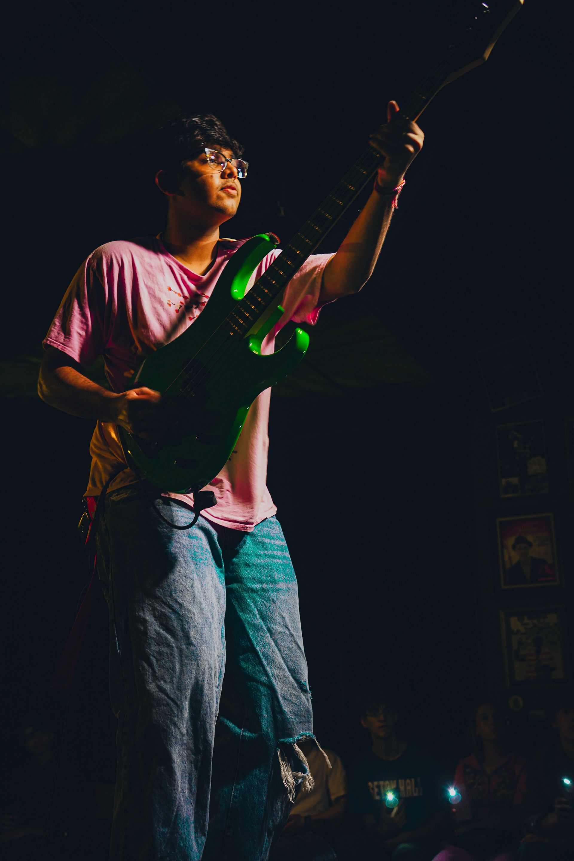 A man is playing a guitar on a stage in the dark.