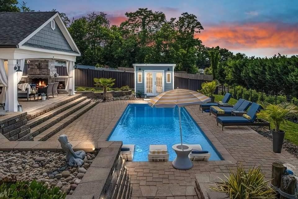 A large swimming pool is in the backyard of a house