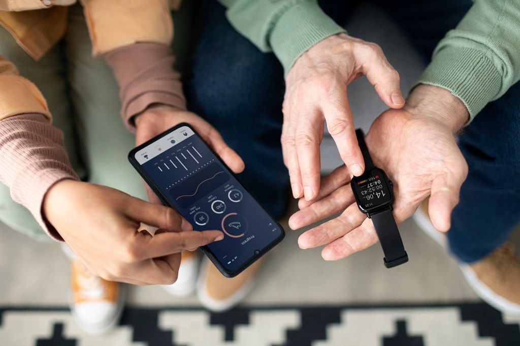 Um par de mãos está segurando um celular e um relógio em mãos