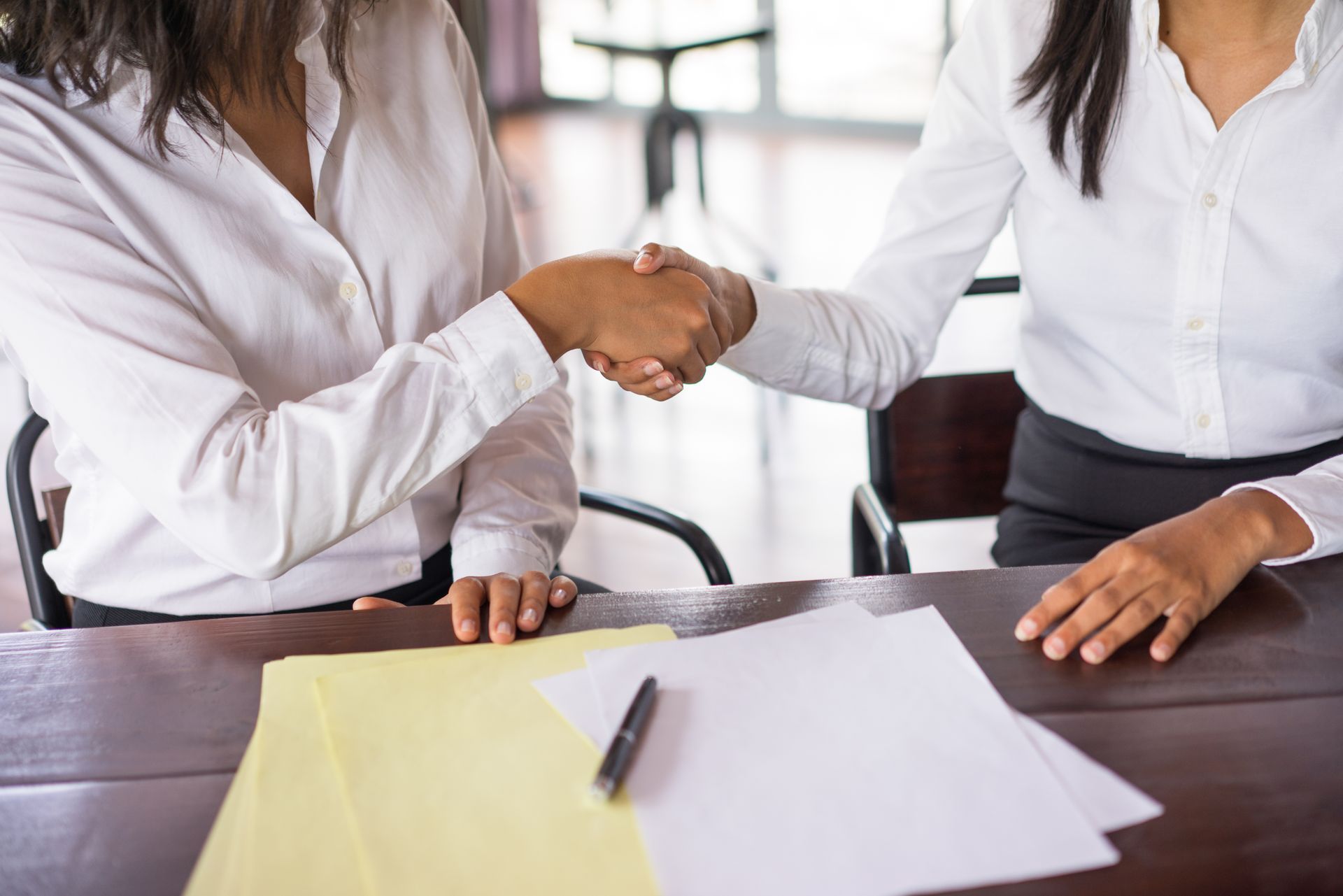 Duas pessoas em um ambiente corporativo apertando a mão ao assinar um acordo