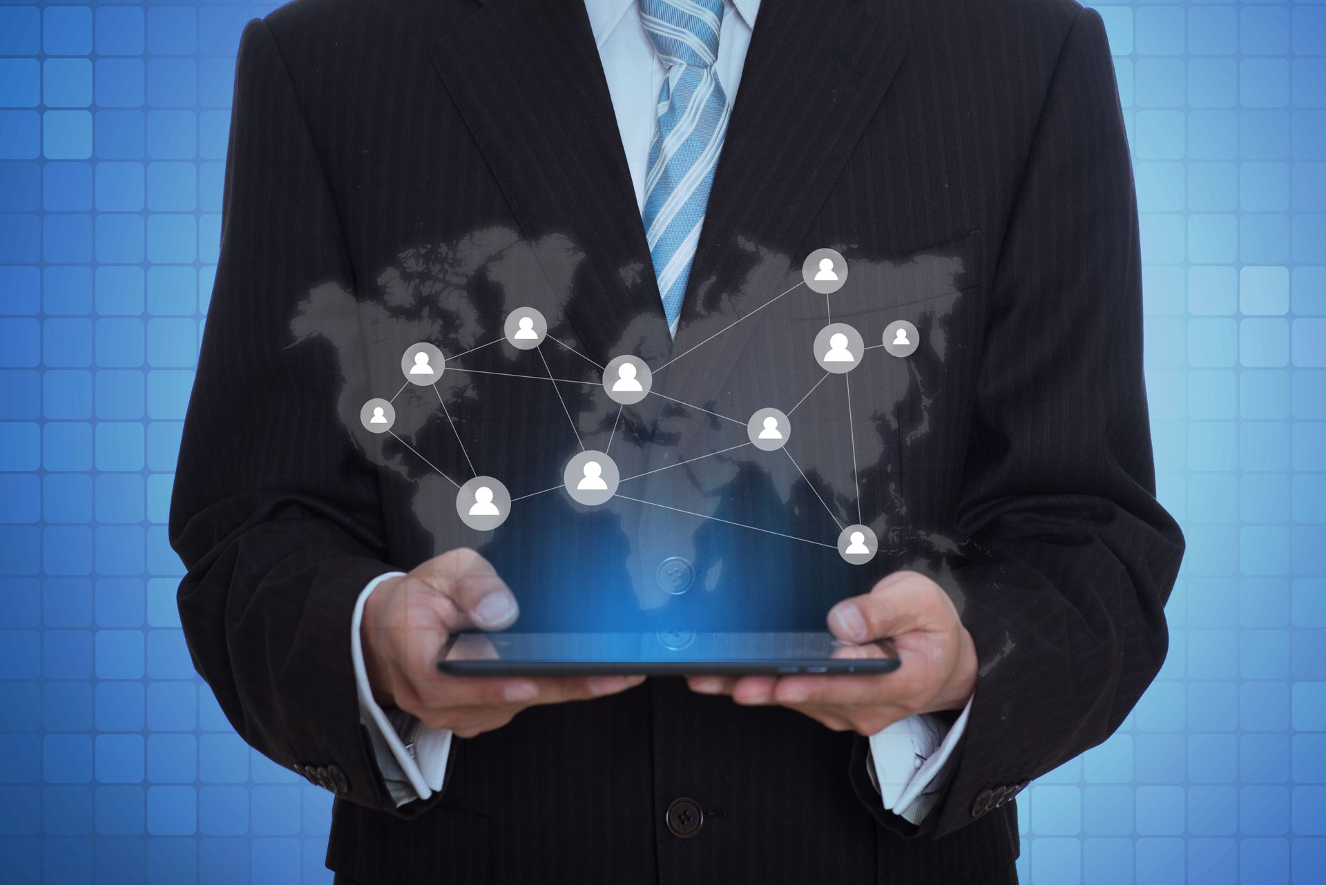 Man in suit holding tablet with a digital world map and connected people icons.