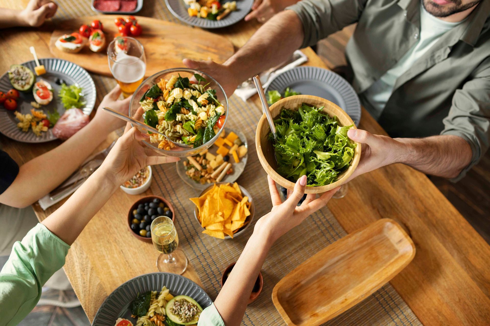 Imagem superior de pessoas fazendo refeição trocando os pratos de salada