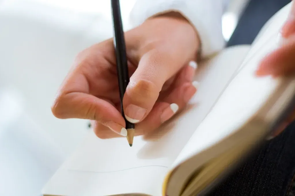 ma mãe femina segura um lápis e escreve em um caderno