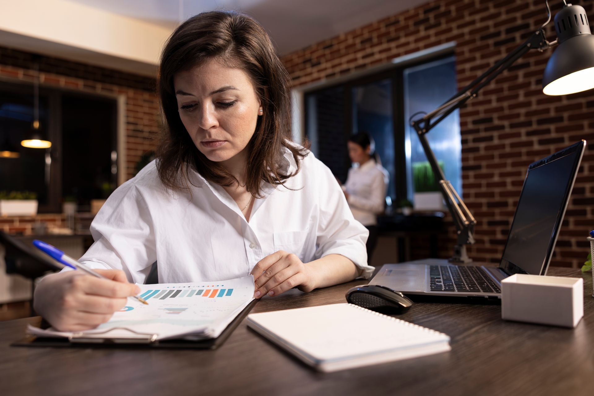 mulher em um escritório sob uma mesa com papéis a mão, calculando taxa de absenteísmo