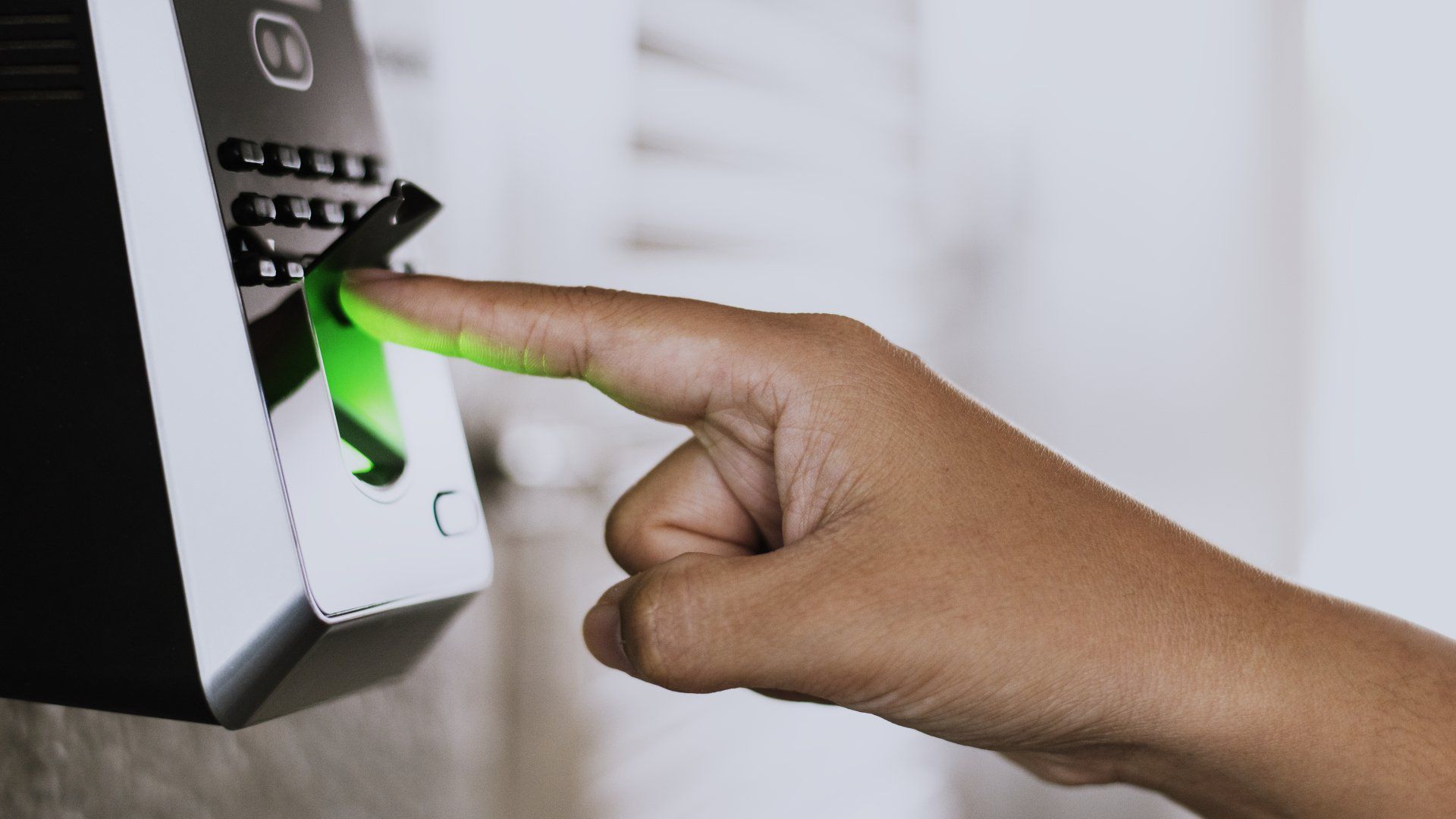 uma mão com o dedo indicador apontado para um dispositivo eletrônico para fazer a leitura da impressão digital
