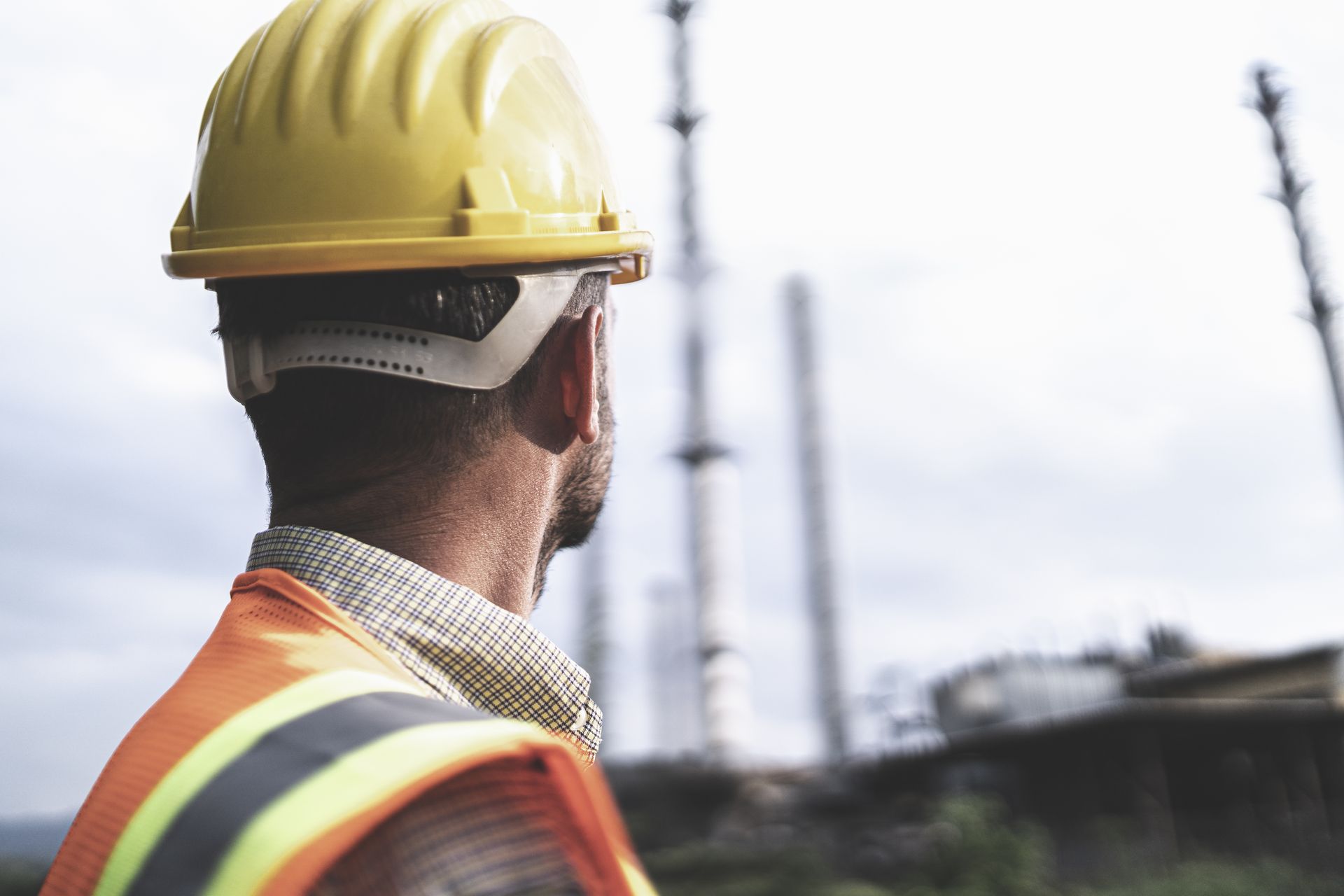 homem com capacete de segurança do trabalho observa canteiro de obras