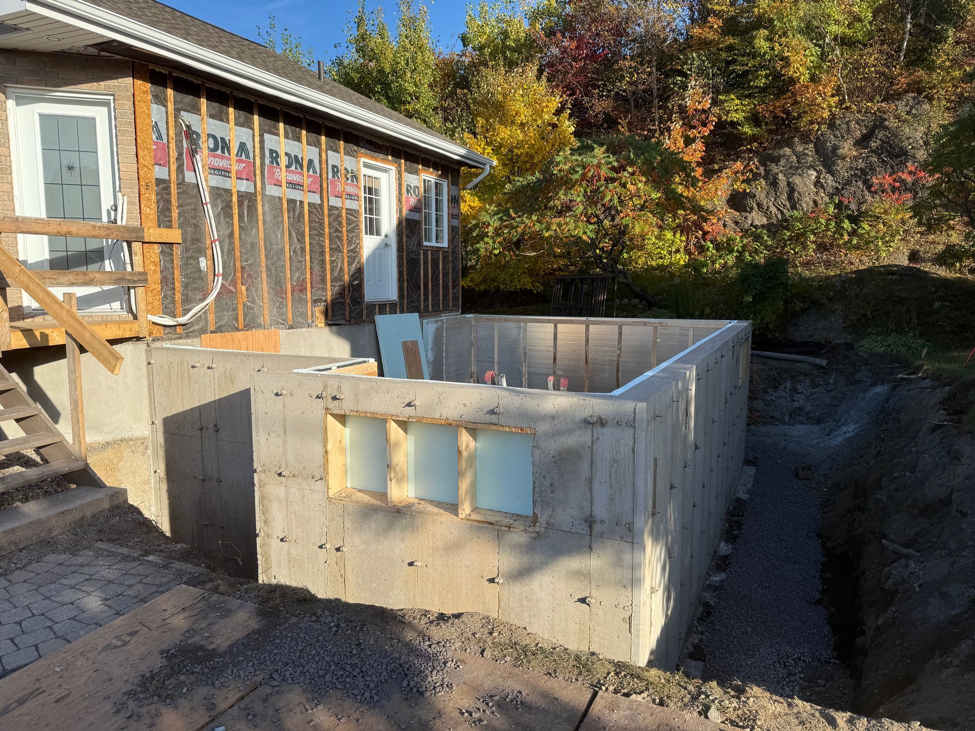Murs de fondation en béton à côté d'une maison en construction dans une cour boisée