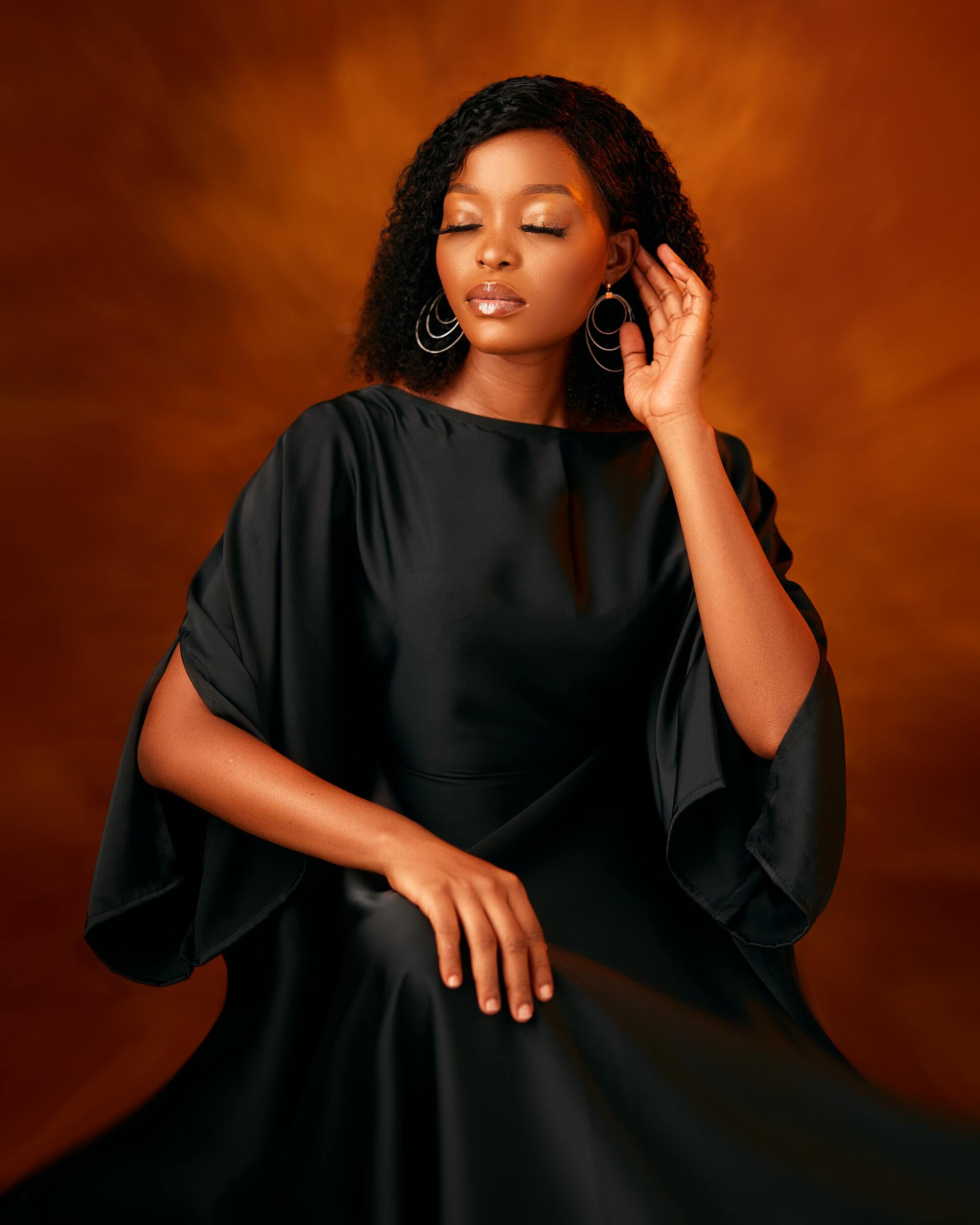A woman in a black dress is sitting down with her eyes closed.