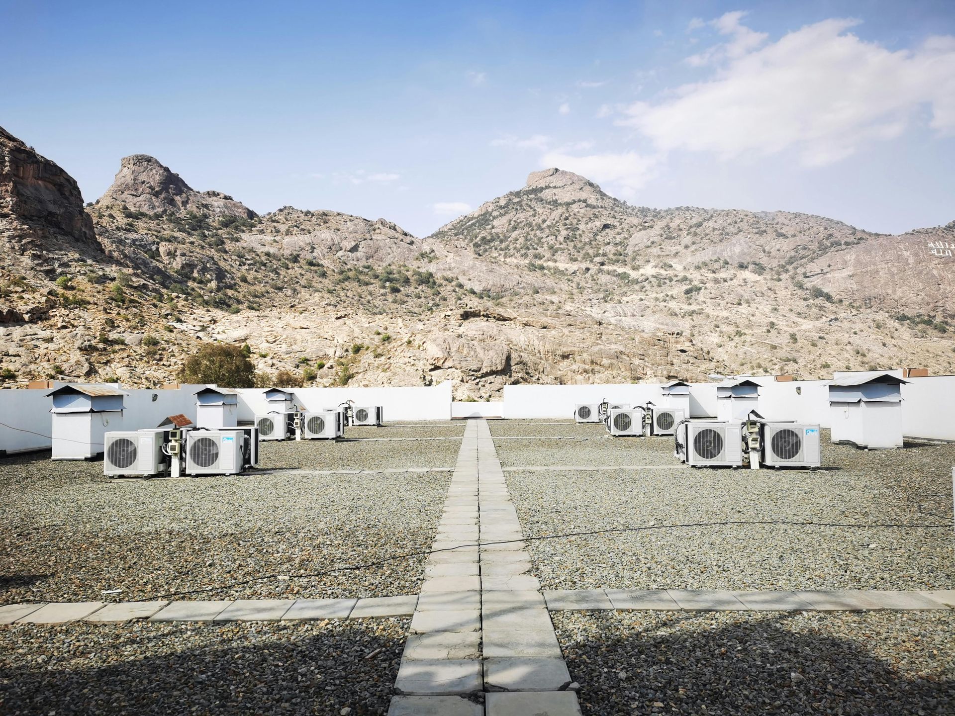 A row of air conditioners on the roof of a building with mountains in the background