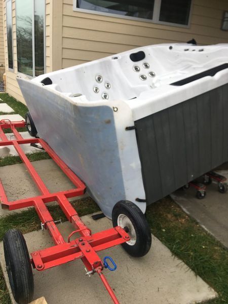 A hot tub is on a red trailer in front of a house