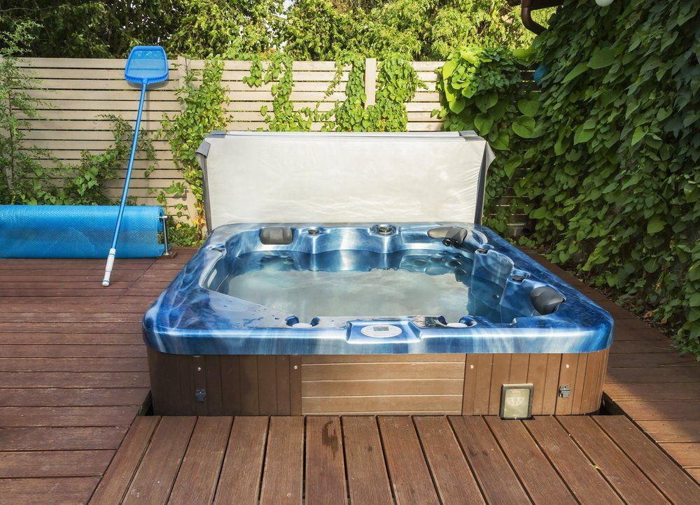 A blue hot tub is sitting on a wooden deck.
