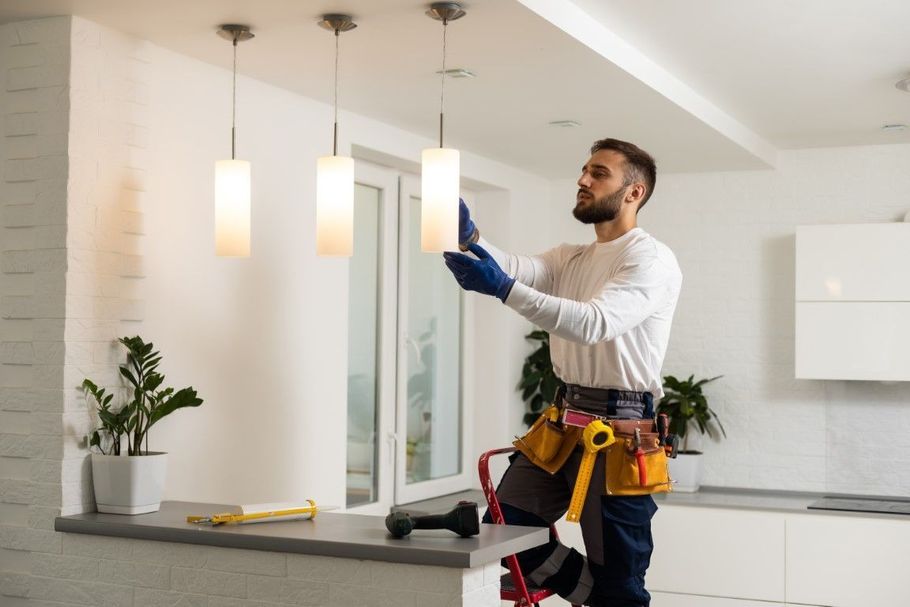 Handyman adjusting a hanging pendant light in a bright kitchen