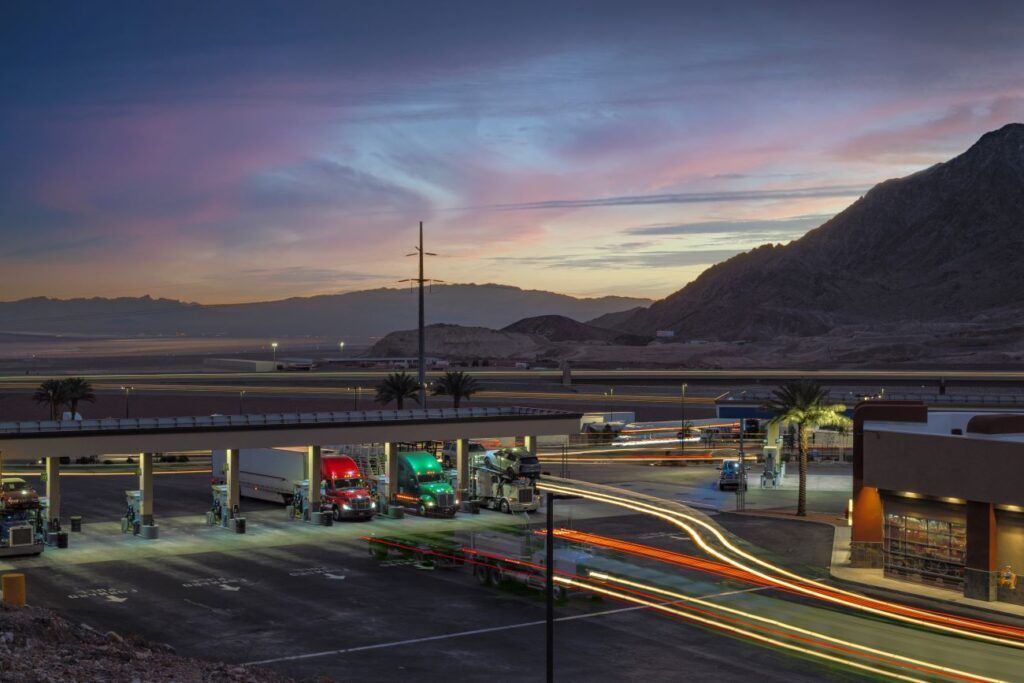 a row of trucks are parked in a rest stop parking lot.