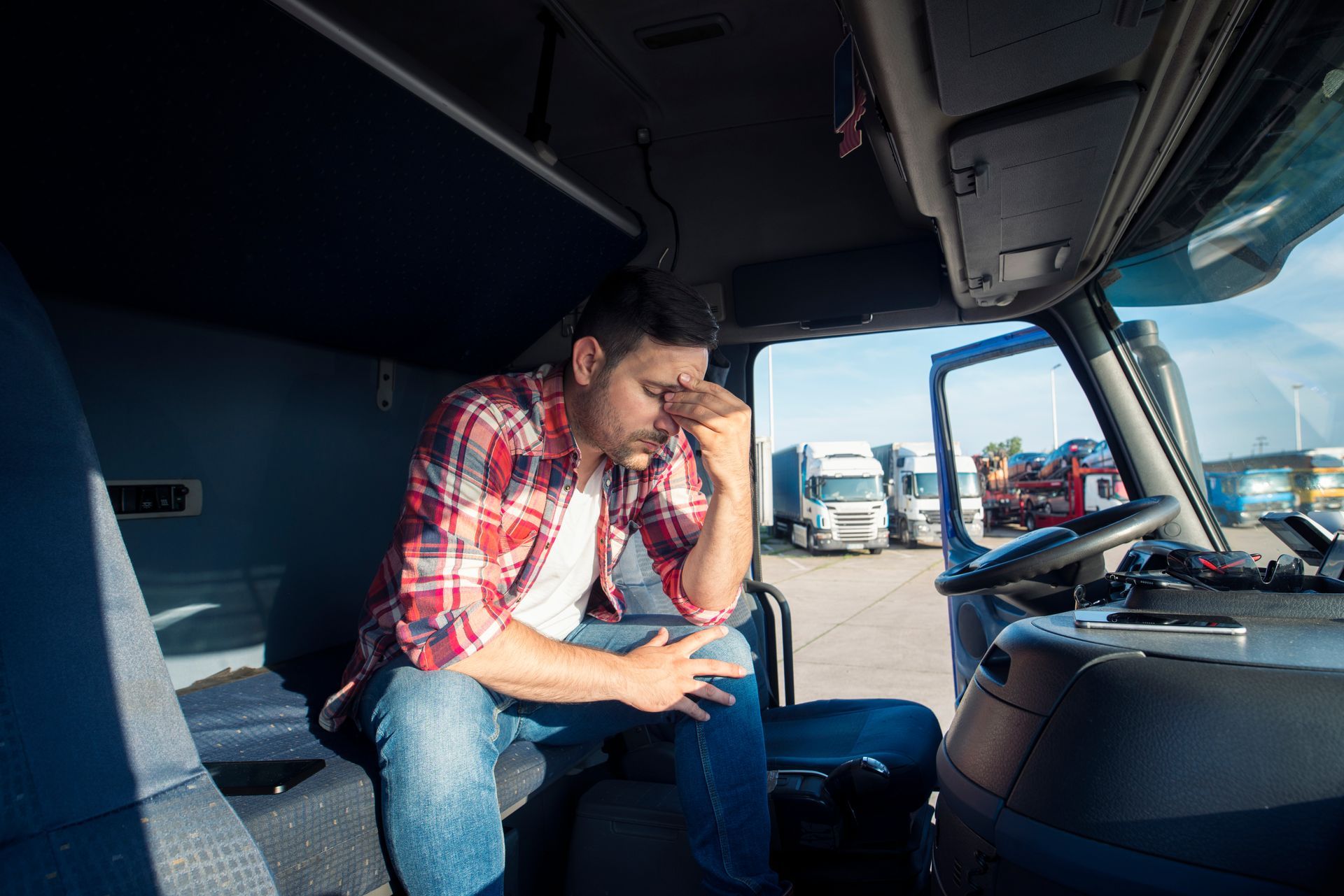 a man is sitting in the back seat of a truck with his head in his hands .