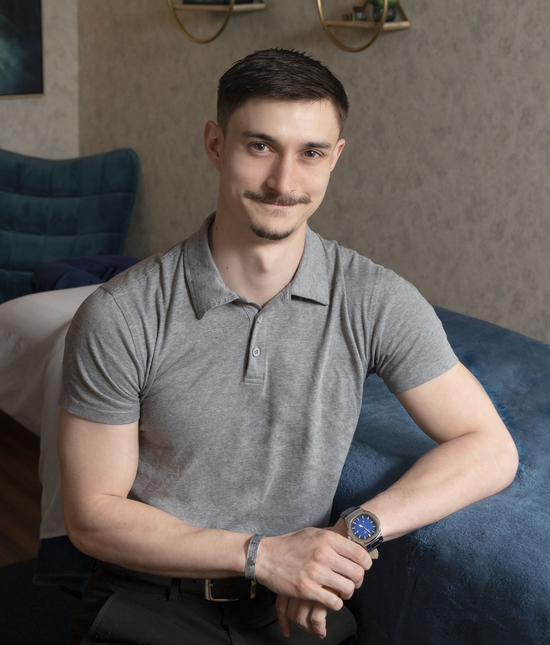 Male massage therapist leaning against massage table with blue blanket