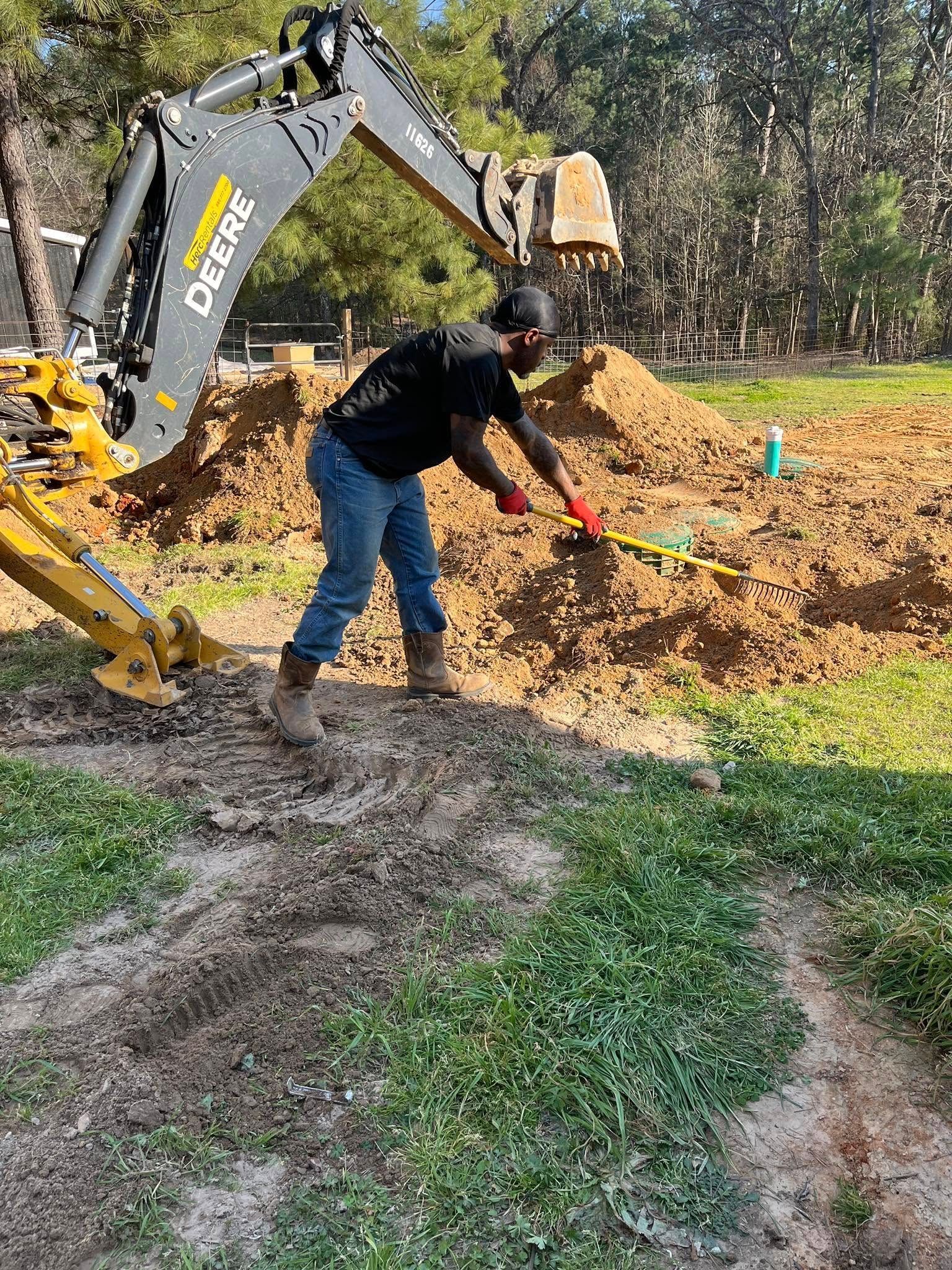 A man is digging a hole in the dirt in front of a bulldozer.
