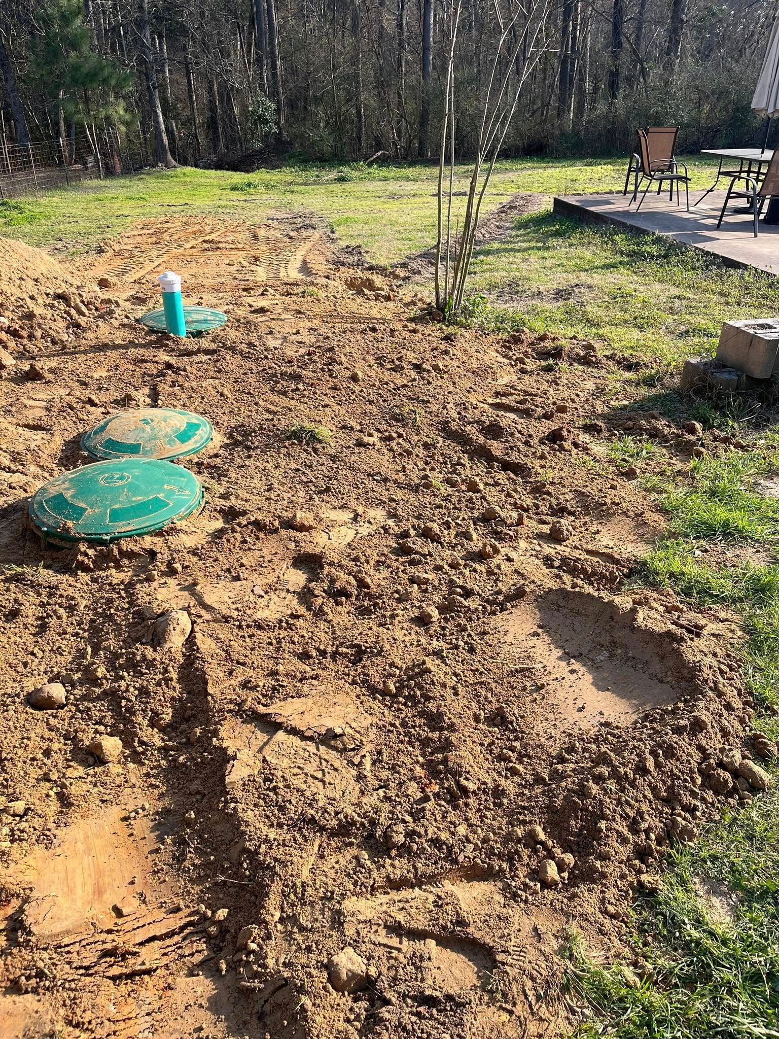 A large pile of dirt is sitting in the middle of a grassy field.