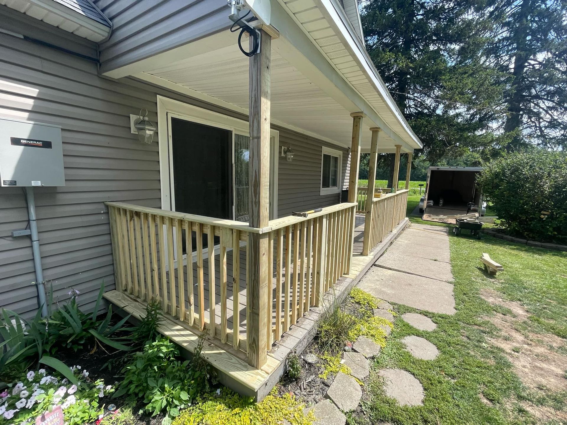 House exterior with a small wooden ramp and porch, stone path, and yard greenery