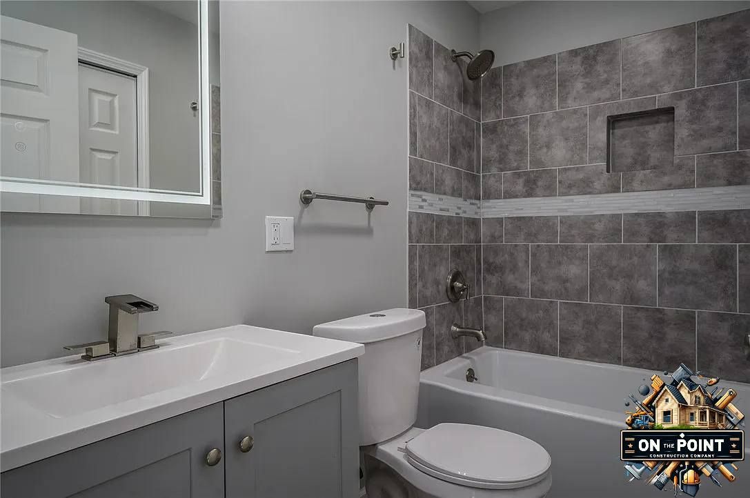 Small bathroom with a sink, mirror, toilet, and a wheelchair near the shower area.