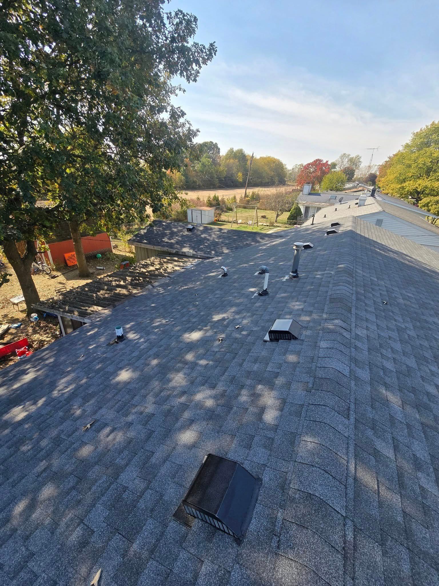Roof under repair with brown shingles, gray underlayment, and tools on a cloudy day