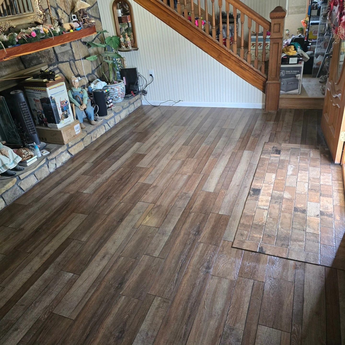 Living room with newly installed wood flooring, fireplace on the left, and stairs in the background