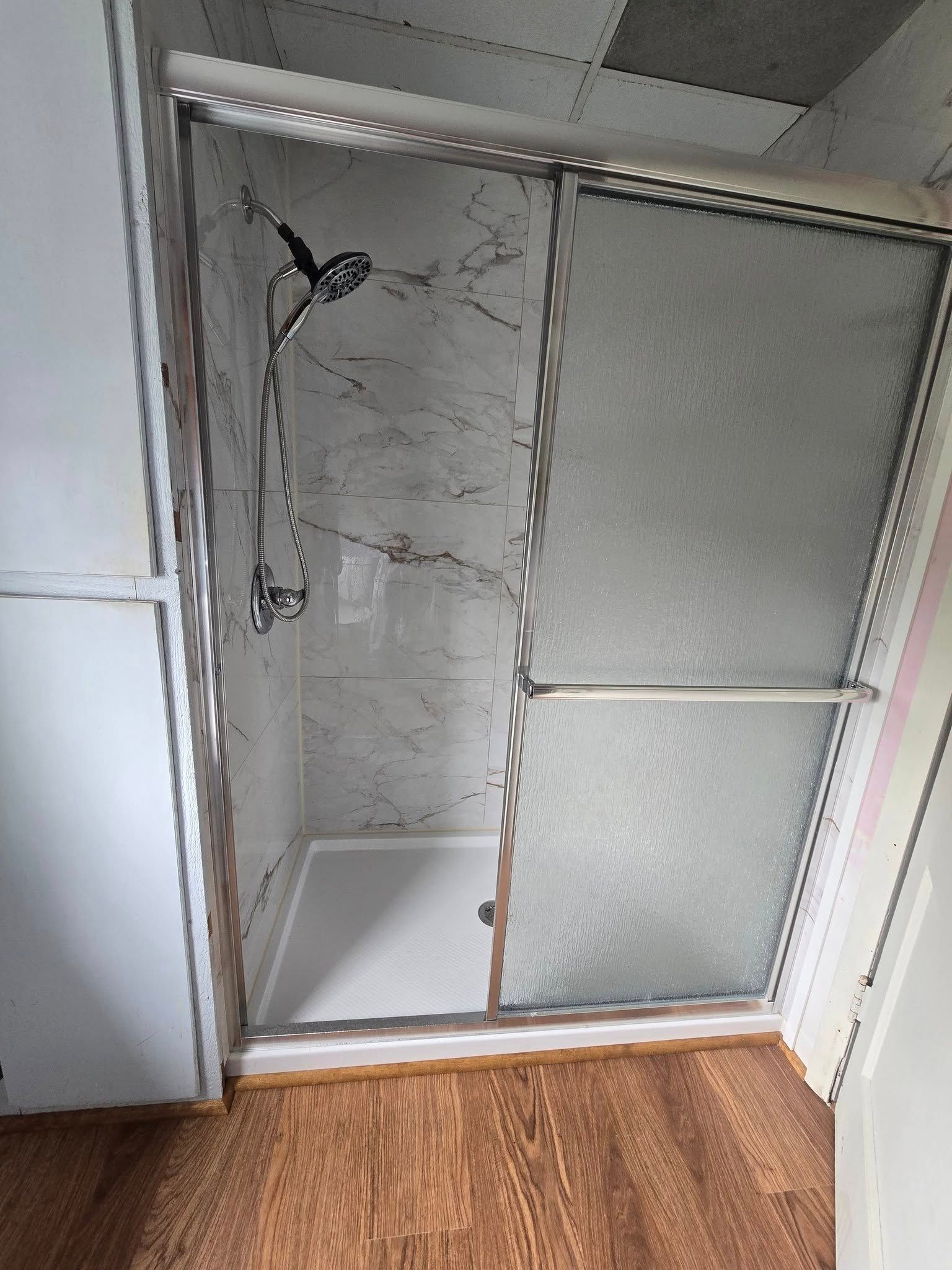Open closet with wire shelving and frosted sliding doors, viewed against a wood floor.