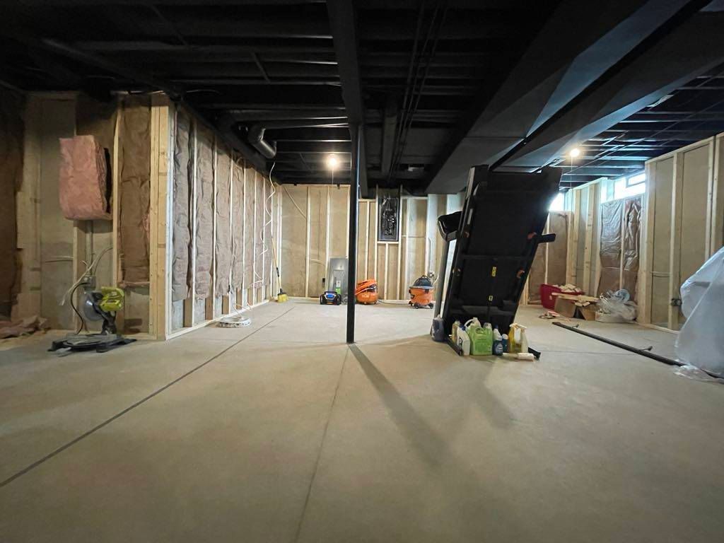 Basement under renovation with exposed framing, concrete floor, and a central support post