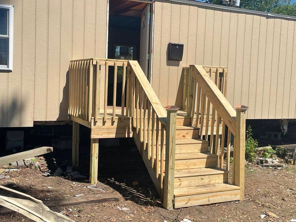 Wooden accessibility ramp and steps leading to a beige building entrance.