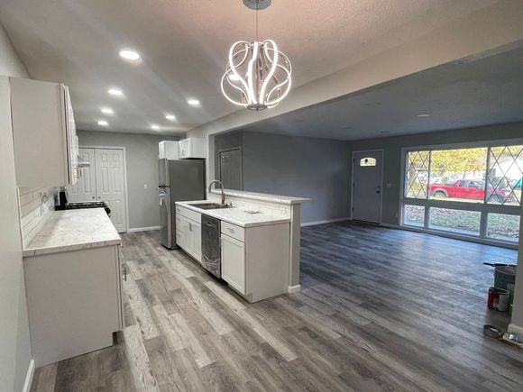 Blue and white kitchen with tiled backsplash, granite counter, and gas stove beneath dark cabinets