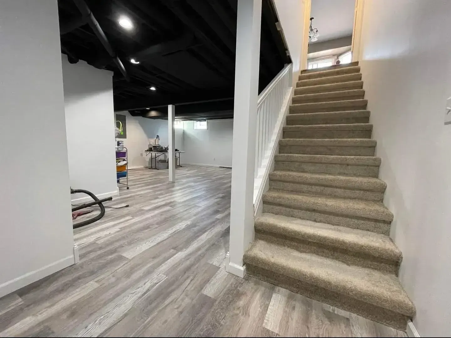 Spacious basement living room with fireplace, TV, sofa, desk, and recessed lighting