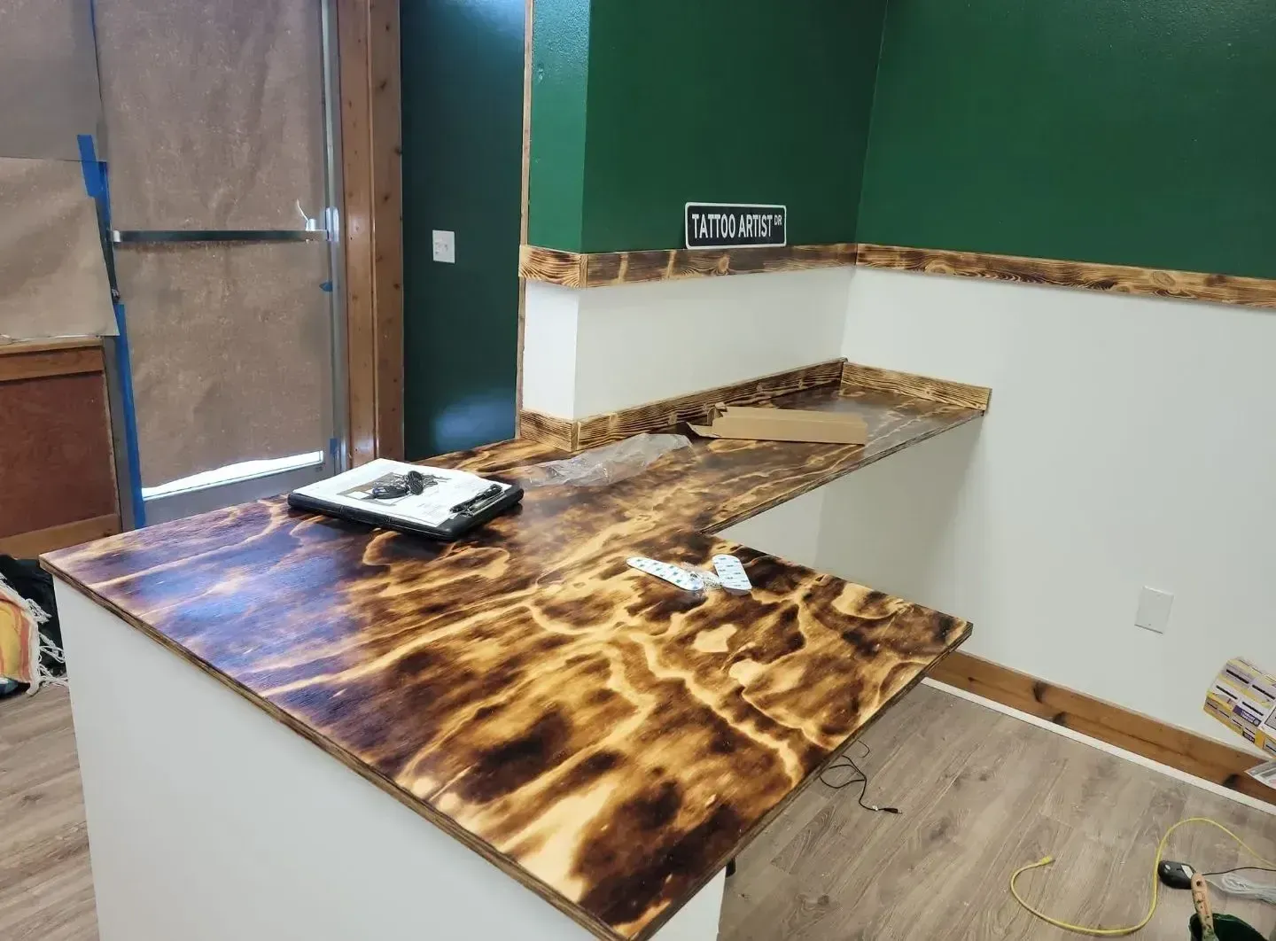 Partially renovated kitchen with wood-look countertops, white walls, and a tray on the island.