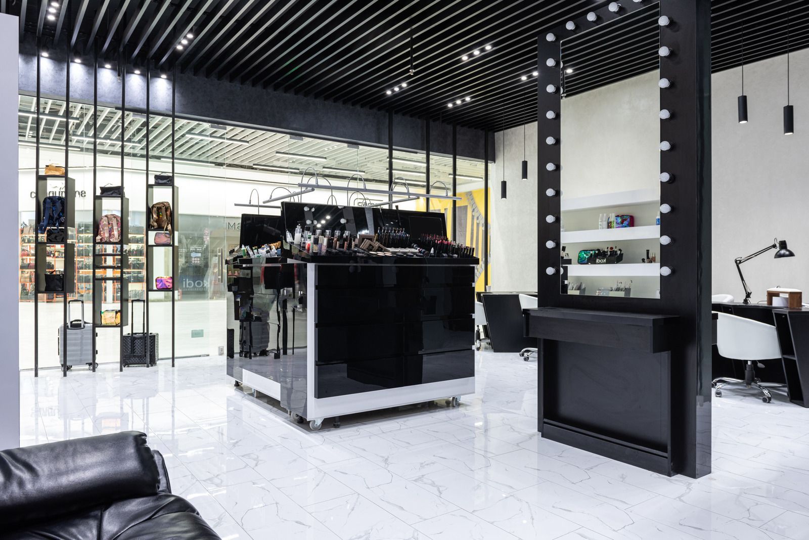 Modern black-and-white salon interior with glossy floor, styling stations, and product display shelves