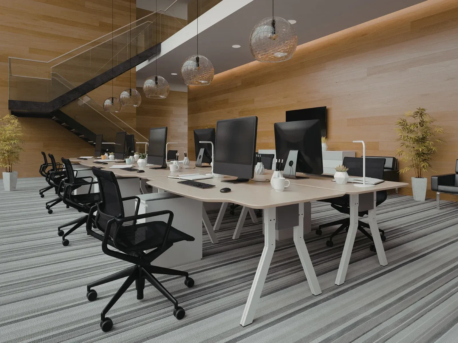 Modern office meeting area with white tables, black chairs, and hanging globe lights under a wood staircase