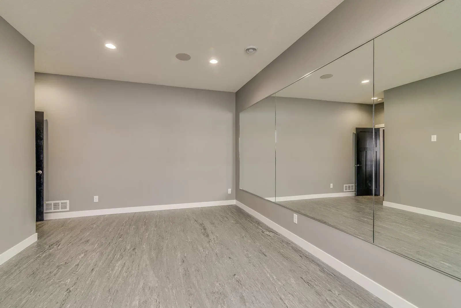 Bright finished basement with carpeted stairs, red rug, TV stand, and white columns.