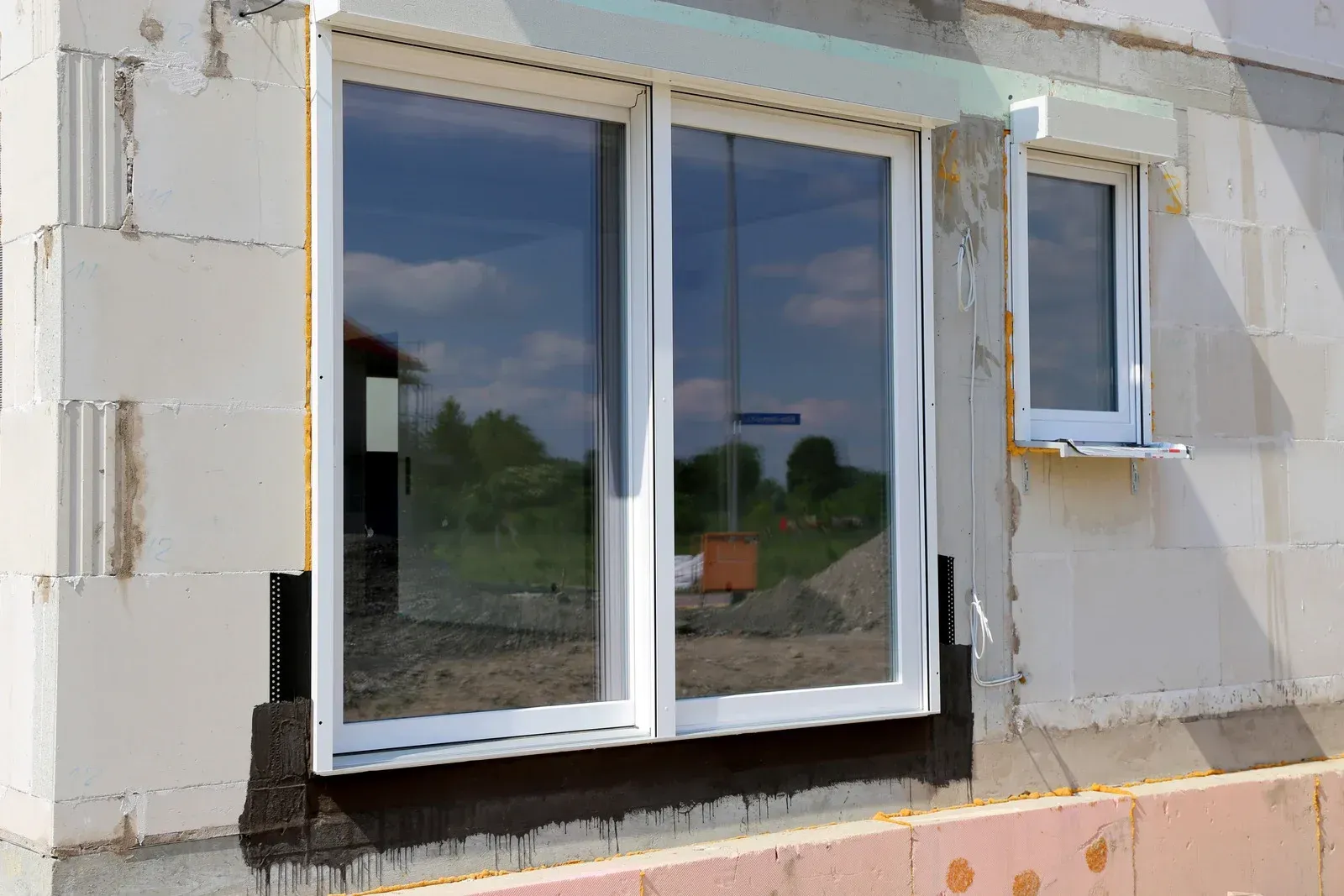 Sliding glass window installed in a wall opening, with white trim and a small adjacent window.