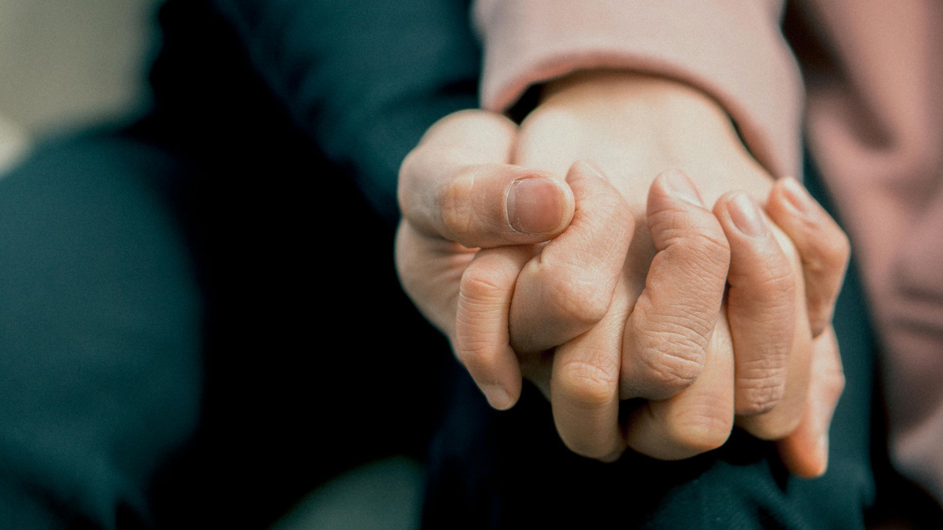 Two hands clasped together, possibly offering comfort or connection.