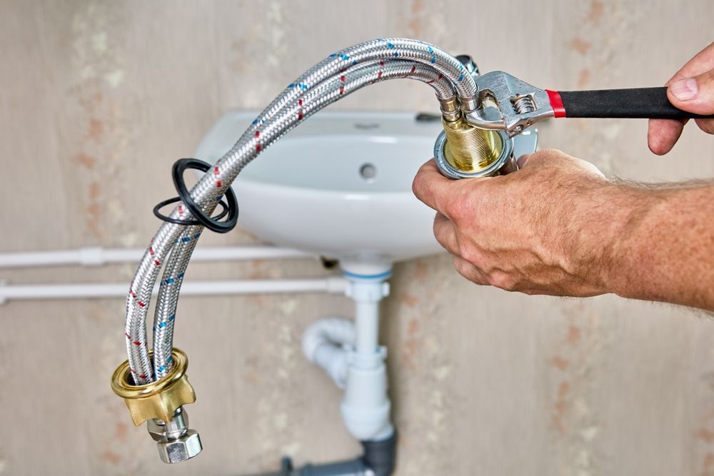 Person Using a Wrench to Connect a Flexible Water Supply Line to A Faucet — Harwood Plumbing & Gasfitting Pty Ltd in Alawa, NT