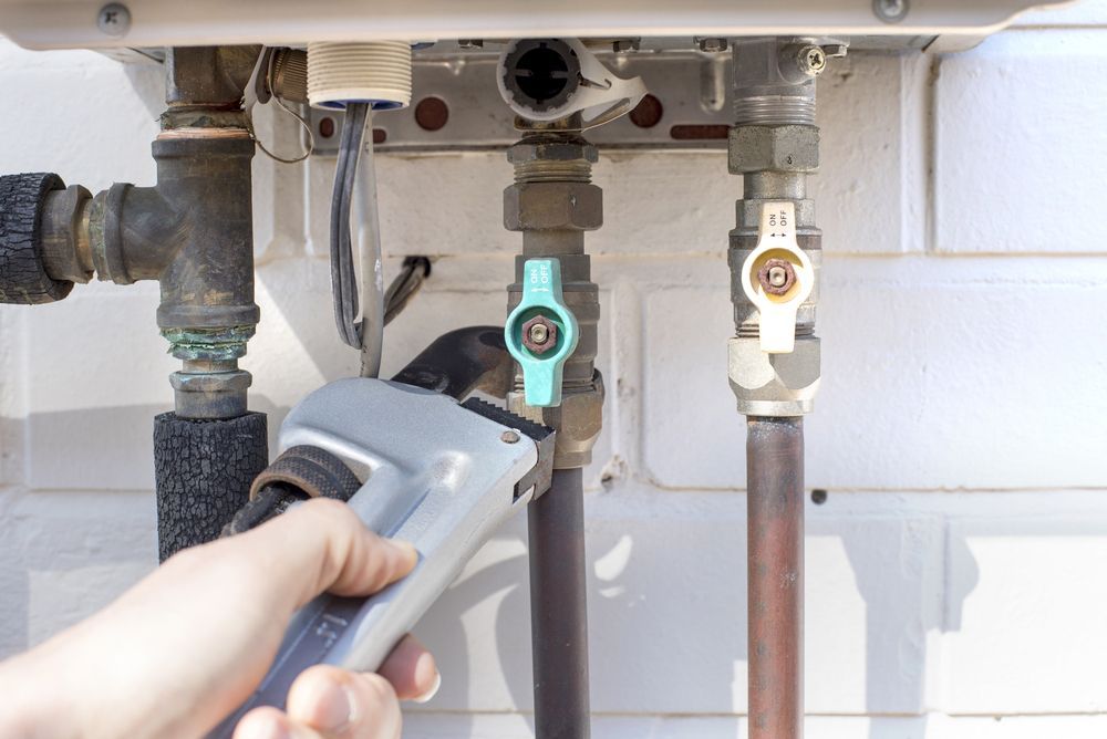 Hand Using Wrench on Water Pipes and Valves Outside — Harwood Plumbing & Gasfitting Pty Ltd in Alawa, NT