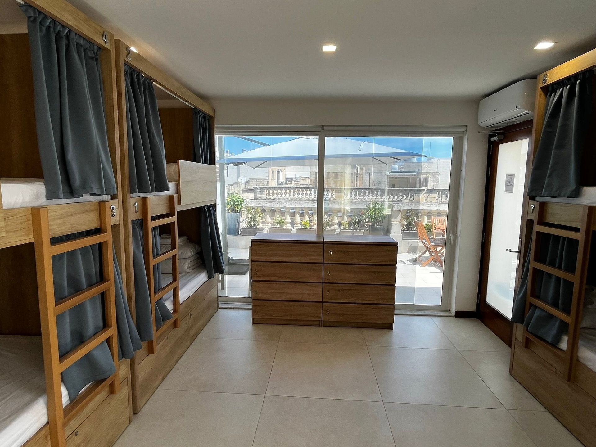 Small bedroom with built-in bunk beds, a dresser, and a large window overlooking a city view.