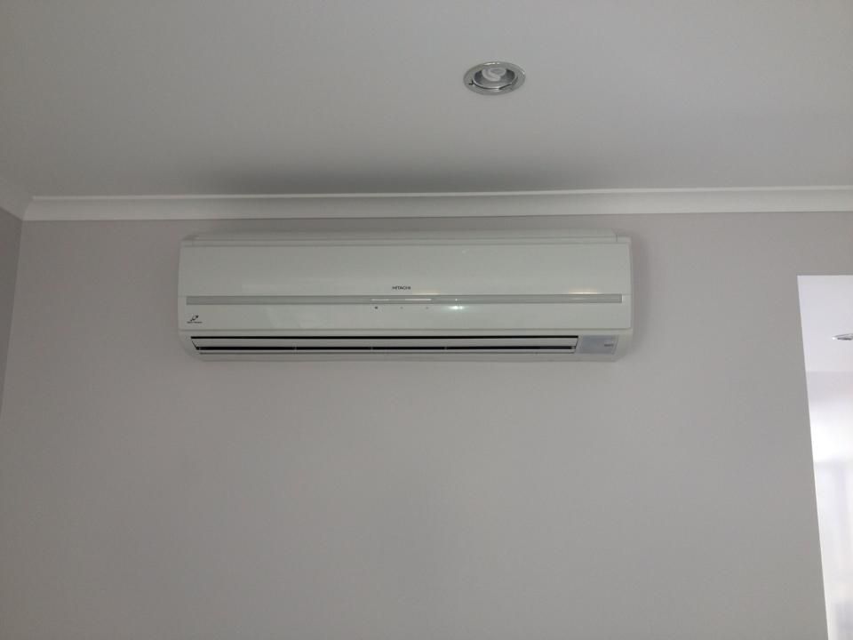 A White Air Conditioner is Mounted on a White Wall — Legit Air Conditioning & Refrigeration in Garbutt, QLD
