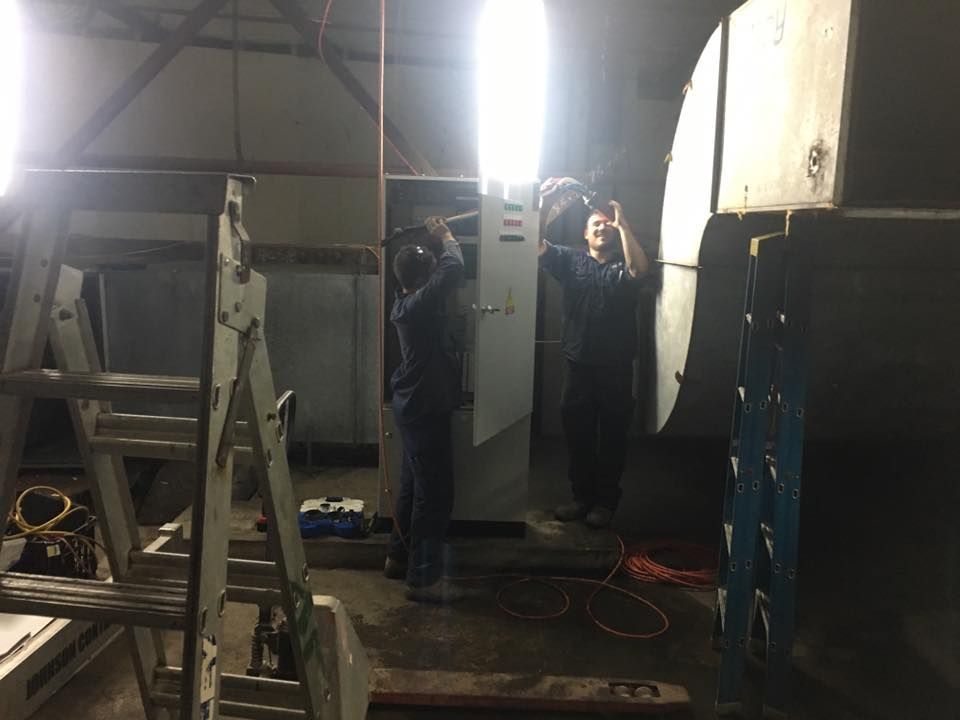 Two Men Are Working on a Machine in a Room With a Ladder — Legit Air Conditioning & Refrigeration in Garbutt, QLD