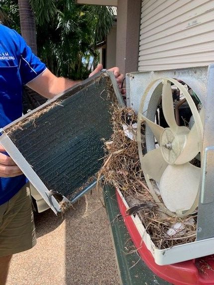 A Man is Holding a Dirty Air Conditioner and a Fan — Legit Air Conditioning & Refrigeration in Garbutt, QLD