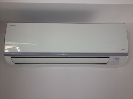A White Air Conditioner is Hanging on a White Wall — Legit Air Conditioning & Refrigeration in Garbutt, QLD