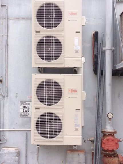 Three Air Conditioners Are Stacked on Top of Each Other on the Side of a Building — Legit Air Conditioning & Refrigeration in Garbutt, QLD